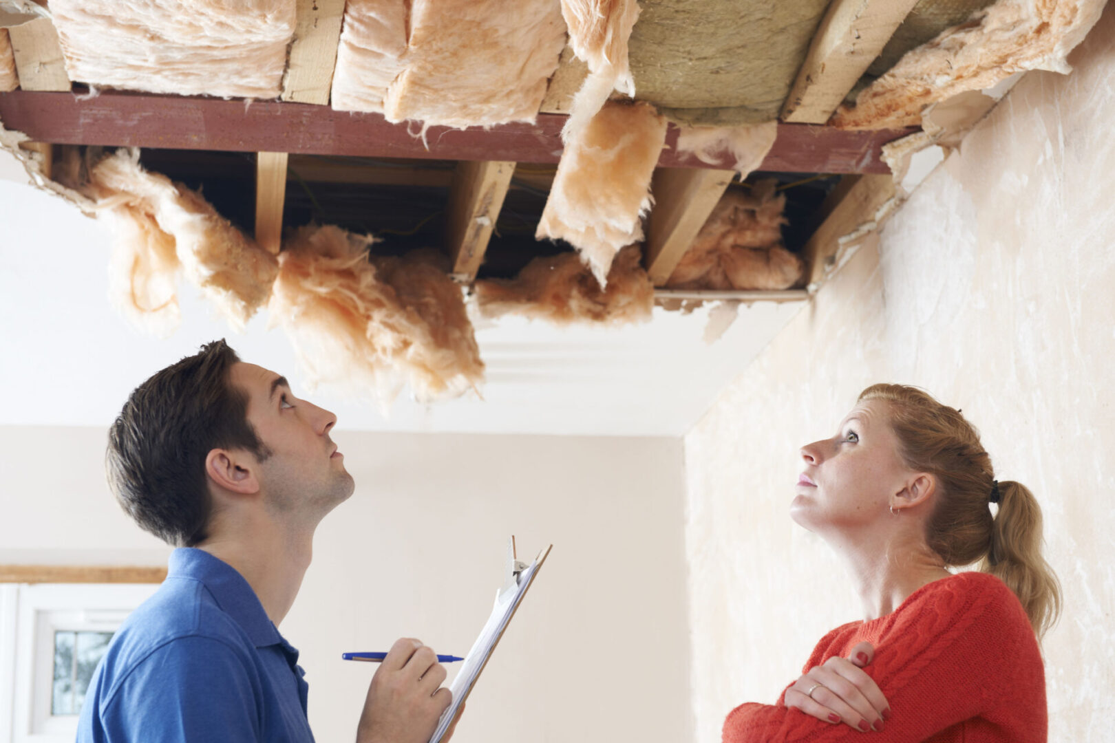 Two people looking at a ceiling in the middle of a room.