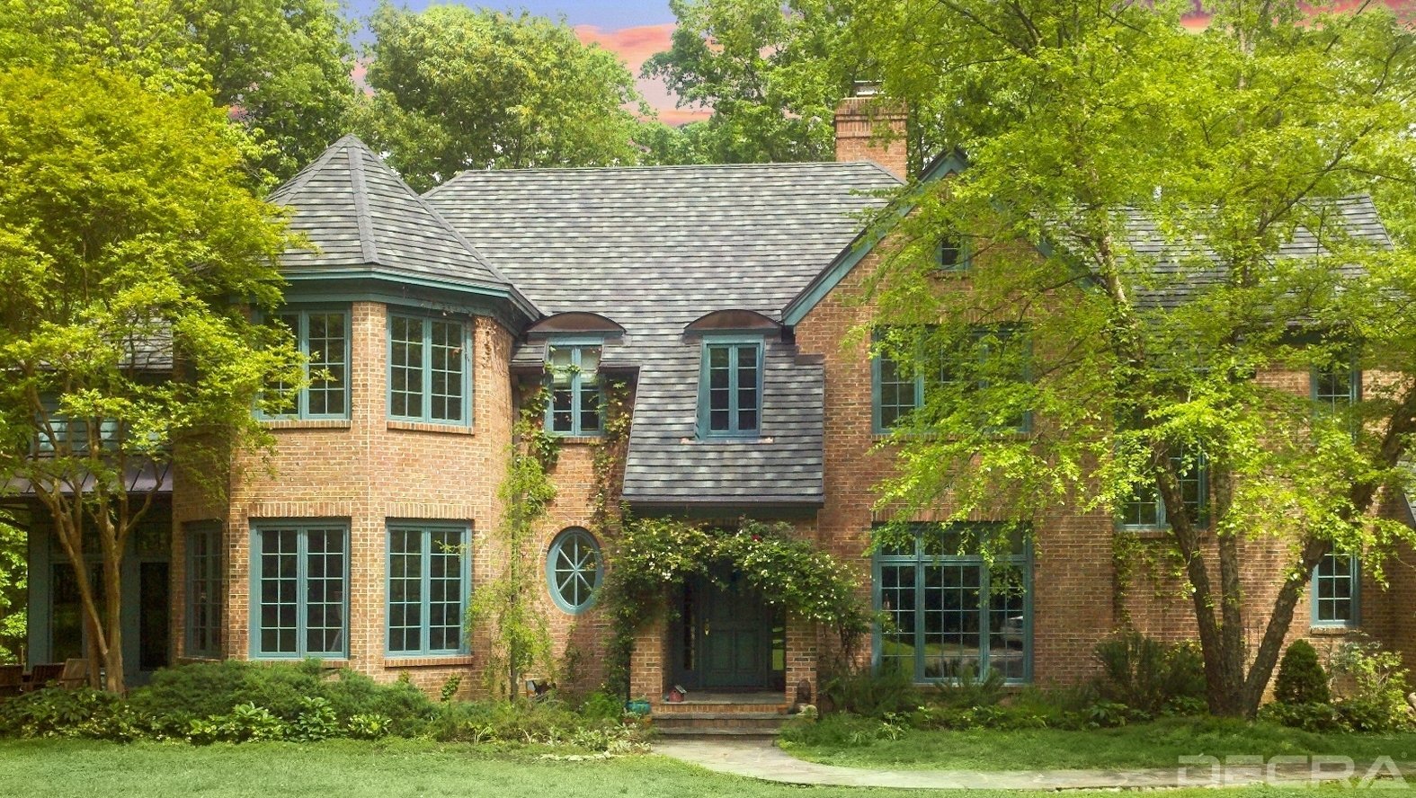 A brick house with green trim and windows.